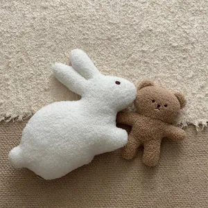 Detailed close-up of cute white rabbit and brown bear plush toys on soft textured carpet background.