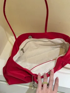 Detail view of the red nylon tote bag interior, showing canvas lining and zipper pocket.