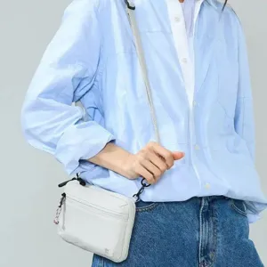 Close-up detail of the multi-pocket crossbody bag showing zipper pocket and strap.