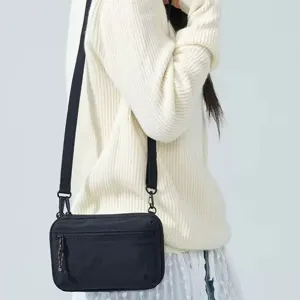 Detail view of black crossbody passport bag worn on shoulder, minimalist design with zipper.