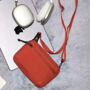 Red nylon crossbody bag detail view showing zipper pocket and adjustable strap design