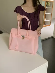 Close-up view of the pink PVC jelly tote bag with metal lock detail and dual top handles.