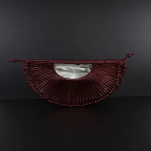 Detailed view of handmade woven half-moon crescent handbag in burgundy with white inner pouch.