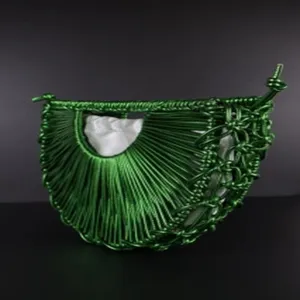 Handcrafted green braided rope crescent handbag detail showcasing intricate knotting and white inner pouch.