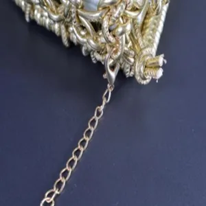 Gold metal chain strap and woven bag detail close up view, stylish accessory for crossbody bag.
