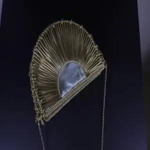 Gold metal fan-shaped evening clutch bag detail, showing unique bar structure and chain strap.