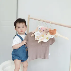 Detailed view of cute wooden clothes hanger with bear design in cozy nursery display setting.