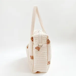 Gesteppte Wickeltasche mit süßer Bärenstickerei, praktischer Seitentasche und stabilen Griffen.