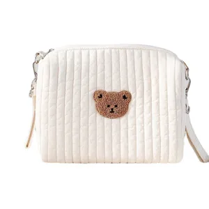 Weißte gesteppte Wickeltasche mit Bärenstickerei, mehreren Taschen und praktischen Gurten.