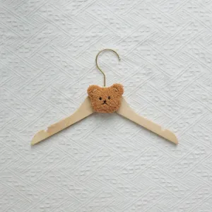 Wooden children clothes hanger with cute plush bear head detail for nursery room organization.