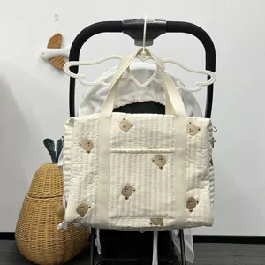 Gesteppte Wickeltasche mit süßem Bärenstickerei, mehreren Fächern und Kinderwagenriemen.