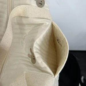 Detailansicht der gesteppten Wickeltasche mit niedlicher Tierstickerei und Außentasche.