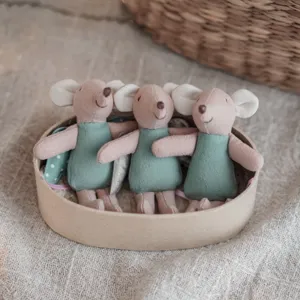 Close-up detail of three cute mini plush mouse toys in a round box, soft fabric texture.