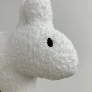 Close up of white plush rabbit toy detail, fluffy boucle fabric texture, cute long ears design.