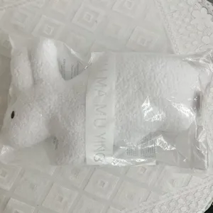 White plush rabbit doll detail view, soft fluffy long ear stuffed toy in protective bag.