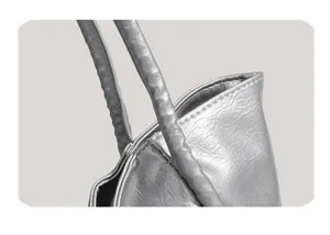 Close-up detail of silver metallic tote shoulder bag showing handles and stitching texture.