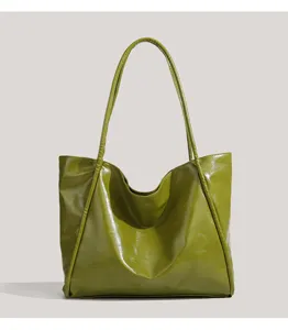 Detailed view of glossy olive green faux leather tote bag, showing fine texture and stitching.
