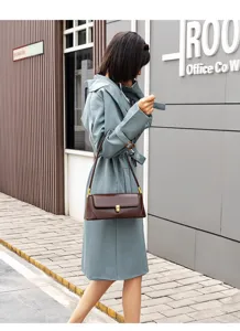 Detail view of stylish brown leather underarm baguette shoulder bag worn by model outdoors.