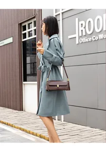 Detailed shot of brown leather baguette shoulder bag with metallic lock, elegant daily style.
