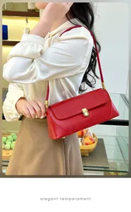 Close-up detail shot of a stylish red leather baguette shoulder bag with gold metal hardware.