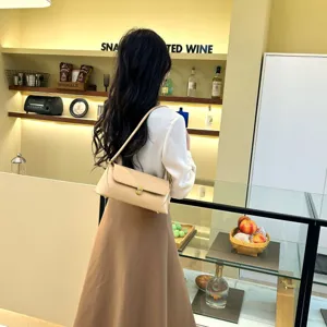 Detail view of the elegant beige baguette shoulder bag with metal lock and slim strap.