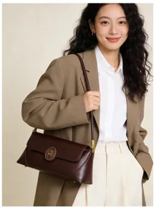 Detailed view of the stylish dark brown leather baguette shoulder bag with metallic accent.