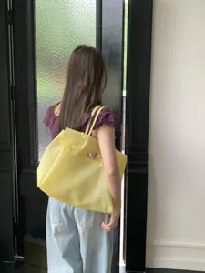 Detailed view of a bright yellow PVC jelly tote bag worn on shoulder in lifestyle setting