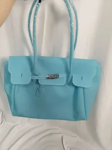Light blue PVC jelly tote bag with shoulder strap and metal lock closure, spacious design.