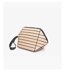 Detail view of the geometric paneled clutch bag with wrist strap, showing unique grid texture.