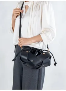 Black woven faux leather crossbody bag with drawstring closure and stylish intertwined design.
