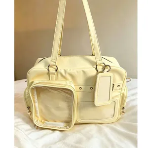 Light yellow Ita bag with clear display windows for pins, badges, and plushies. Daily shoulder tote.