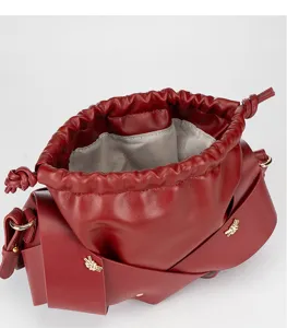 Detailed view of the wine red leather drawstring shoulder bag with metallic knot accents.