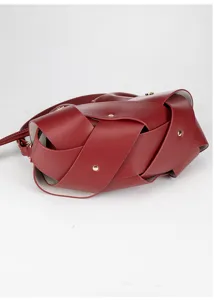 Detailed view of women wine red woven shoulder crossbody bag with wide leather straps.