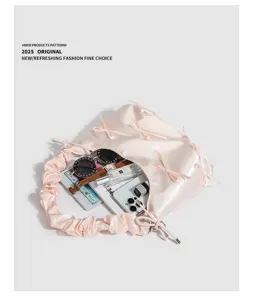 Vista dettagliata dall'alto di una borsa a spalla in satin rosa con fiocchi e accessori vari.