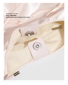 Primo piano dei dettagli interni della borsa in raso rosa con chiusura magnetica e zip.