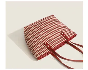 Red houndstooth tote bag detail, woven fabric with red leather trim and shoulder straps.