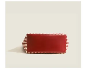 Detailed view of the red houndstooth tote bag bottom, showing durable leather and fine stitching.