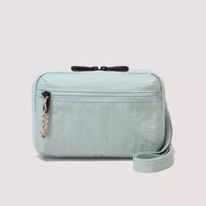 Light blue crossbody passport bag detail, compact small square bag with zipper pocket.