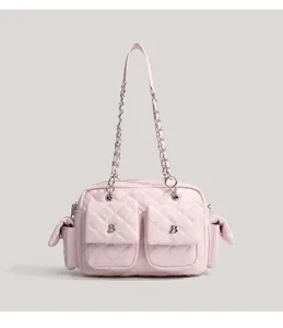 Detailed view of the pink quilted shoulder bag featuring dual front pockets and metal chains.