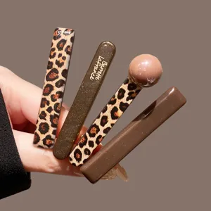 Close-up detail of stylish leopard print and brown bobby pins set, chic hair accessories.
