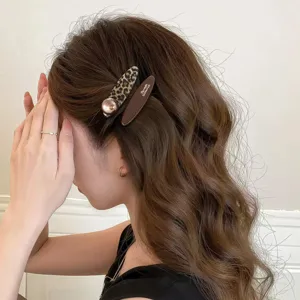Closeup detail of a chic leopard print and brown hair clip worn on wavy hair side.