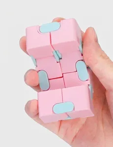 Nahaufnahme des rosa-blauen Macaron Infinity Cube Anti-Stress-Spielzeugs in Hand.
