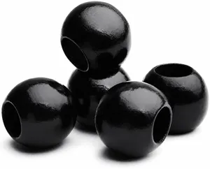 Gros plan de perles rondes en bois noir avec des trous percés pour accessoires de bijoux DIY.