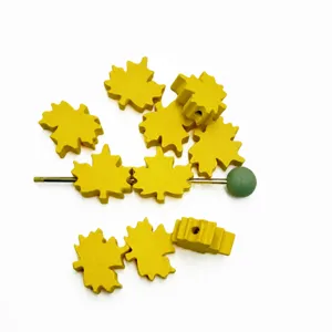 Close-up of yellow maple leaf shaped wooden beads, ideal for DIY handmade jewelry accessories.
