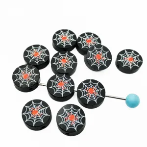 Close up of black round wooden beads with white spider web and red spider pattern details.