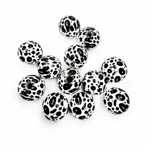 Close-up view of 16mm black and white cow print wooden beads, ideal for DIY crafts.