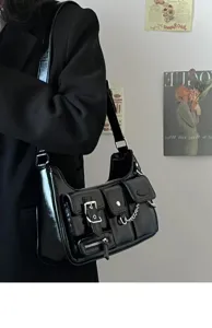 Black patent leather shoulder bag detail with multiple front pockets, metal buckles and chain.