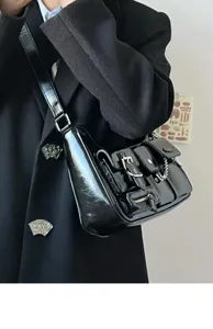 Close-up of stylish black patent leather motorcycle shoulder bag with multi pockets and chain.