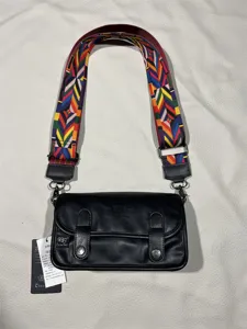 Close-up detail of the vintage crossbody bag showing the colorful wide woven strap.