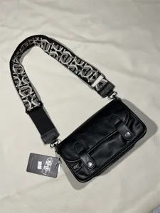 Black retro small shoulder bag with wide patterned strap and metal hardware details.